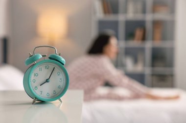 Evde yatakta egzersiz yapan genç bir kadın. Çalar saate odaklan. Sabah rutini