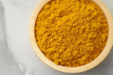 Açık gri masadaki kasede zerdeçal tozu, üst manzara.