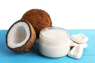 Açık mavi ahşap masada beyaz arka planda hindistan cevizi ve pişirme yağı