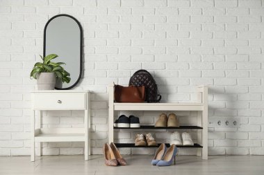 Ayakkabı bankı, farklı ayakkabılar ve ev bitkisi.