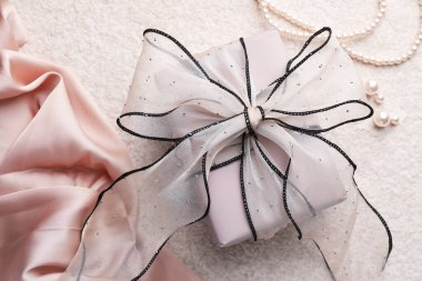 Işık desenli arka planda güzel fiyonklu ve inci takılı hediye kutusu, üst manzara.