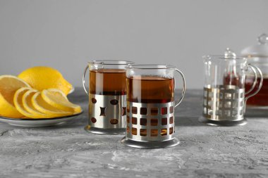 Gri dokulu masada servis edilen metal tutacaklı çay bardakları.