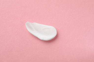 Açık pembe arka planda vücut kremi kokusu, üst manzara.