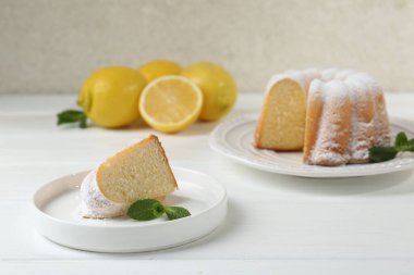 Lezzetli limonlu kek, pudra şekeri ve nane şekeri beyaz ahşap masada.