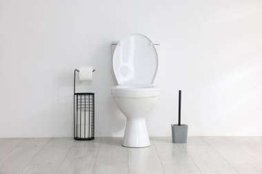 Beyaz duvarın yanında tuvalet, fırça ve ihtiyaçlar