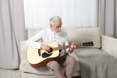 Rahatlatıcı hobi. Son sınıf öğrencisi evdeki kanepede gitar çalıyor.