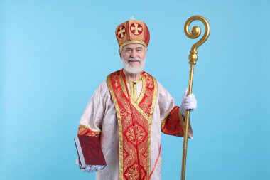 Açık mavi arkaplan üzerine kitabı olan Aziz Nicholas