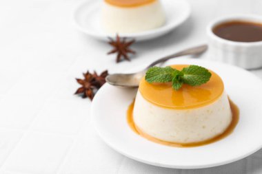Tasty pudding with caramel sauce served on white tiled table, closeup. Space for text