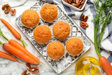 Lezzetli havuçlu kekler, taze sebzeler ve beyaz mermer masada cevizler, düz uzanmış.