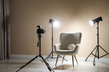 Profesyonel ışıklandırma ekipmanları ve fotoğraf stüdyosunda dekoratif yastıklı koltuk.