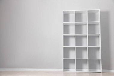 Empty shelving unit near light grey wall indoors. Space for text
