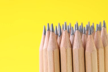Many graphite pencils on yellow background, closeup. Space for text