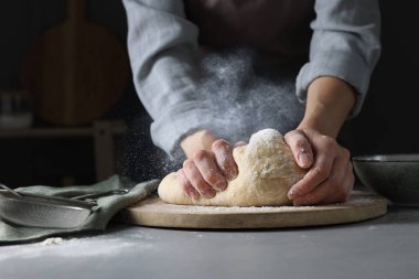Gri masada hamur yoğuran kadın, yakın plan. Un bulutu