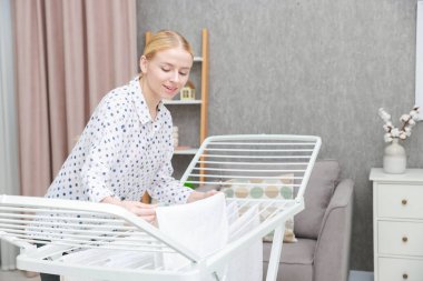 Güzel bir kadın temiz çamaşırları evdeki kuru askısına asıyor.