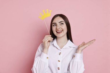 Pembe arka planda kağıt kaplamalı sopa tutan mutlu kadın