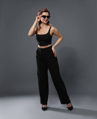 Gri arka planda poz veren mutlu kadın. Pin-up titreşimleri