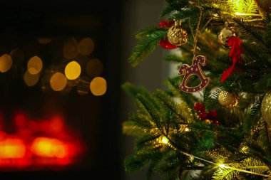 At oyuncağıyla süslenmiş güzel Noel ağacı, diğer süsler ve kapalı mekandaki şenlikli ışıklar, yakın çekim. Bokeh etkisi