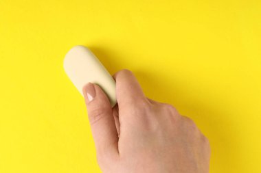 Sarı arkaplanda silgi kullanan kadın, yakın plan