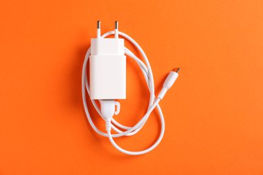 Turuncu arka planda şarj kablosu olan USB güç adaptörü, üst görünüm
