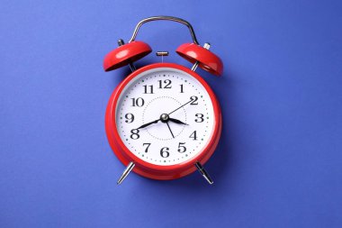 Mavi arkaplanda bir kırmızı alarm saati, üst görünümde.