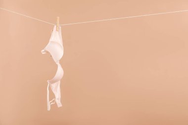 Koyu bej arkaplanda asılı duran güzel sutyen, metin için boşluk