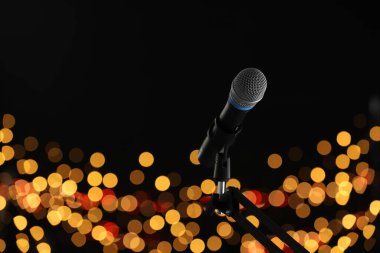 Mikrofon siyah arkaplanda bulanık ışıklarla duruyor, mesaj için yer var. Bokeh etkisi
