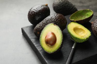 Taze olgun avokadolar ve kaşık gri masada, yakın plan.