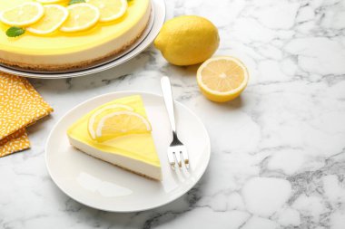 Lezzetli bir parça limonlu cheesecake, çatal ve turunçgil meyvesi beyaz mermer masada, yakın plan. Metin için boşluk