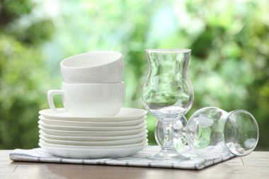 Clean dishware on wooden table against blurred background