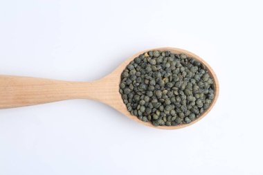Raw lentils in wooden spoon isolated on white, top view