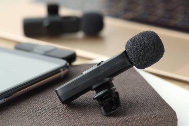 Lavalier mikrofonlar, kablosuz alıcısı ve masadaki not defteri olan akıllı telefon, seçici odaklı.