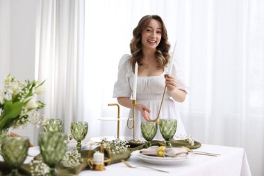 Mutlu genç bayan evde akşam yemeği için sofra kuruyor.