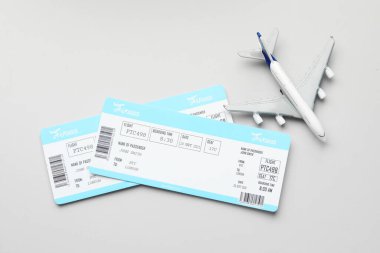 Seyahat acentesi. Uçuş biletleri ve uçak modeli gri arka planda, düz konumda