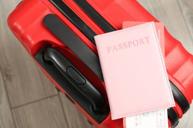 Biletli pasaport ve yerde kırmızı bavul, üst manzara.