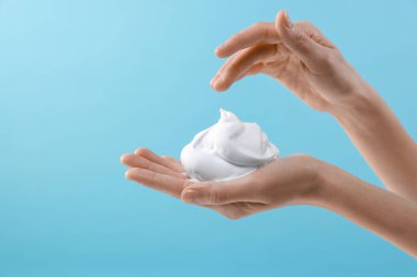 Açık mavi arka planda kozmetik köpüklü kadın, metin için yeri olan yakın plan
