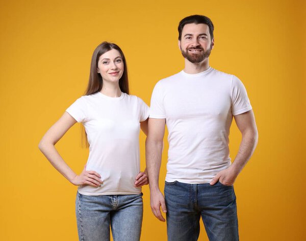 Woman and man wearing blank white t-shirts on orange background. Mockup for design