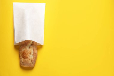 Sarı arka planda taze ekmekli kağıt torba, üst manzara. Metin için boşluk