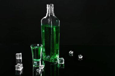 Siyah ayna yüzeyinde Absinthe shot bardağı, şişe ve buz küpleri, metin için boşluk