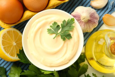 Maydanozlu mayonez sosu ve beyaz ahşap masadaki malzemeler.