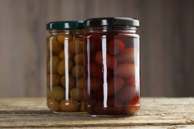 Ahşap masada cam kavanozlarda turşulu zeytin, yakın plan.