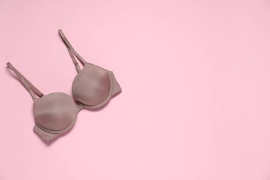 Soluk pembe arka planda güzel koyu bej sütyen, üst manzara. Metin için boşluk