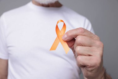 Çoklu Skleroz farkındalığı. Gri arka planda turuncu kurdeleli son sınıf öğrencisi, yakın plan.