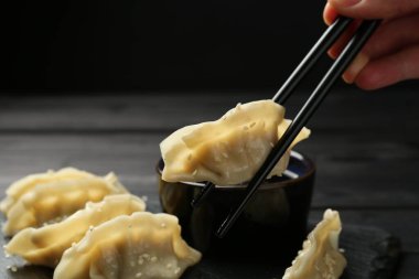 Siyah masada lezzetli gyoza (hamur tatlısı) yiyen bir kadın, yakın plan.