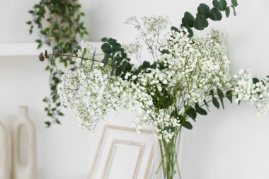 Güzel çigila çiçekleri ve okaliptüs dallarından oluşan buket kapalı alanda, yakın plan.