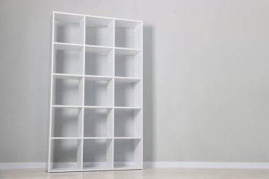 Empty shelving unit near light grey wall indoors. Space for text