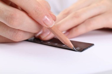 Masada cetvel ve kalemle resim çizen kadın, yakın plan.