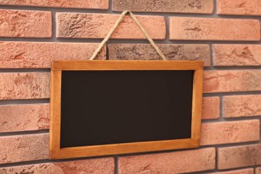 Tuğla duvarda boş küçük bir tahta.