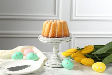 Lezzetli kek, Paskalya yumurtası ve beyaz mermer masada laleler.