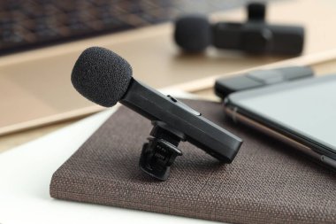 Lavalier mikrofonlar, kablosuz alıcısı ve masadaki not defteri olan akıllı telefon, seçici odaklı.