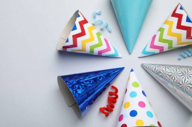 Açık gri arka planda renkli parti şapkaları, düz yatış